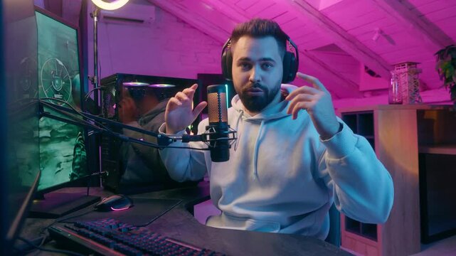 Caucasian smiling talking microphone at camera guy male gamer man streamer influencer blogger in headphones record channel online vlog chat talk e-sport video game cyber sport addict radio presenter