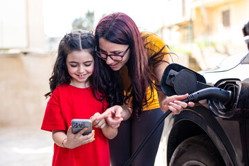 Woman and girl charging ev car at home