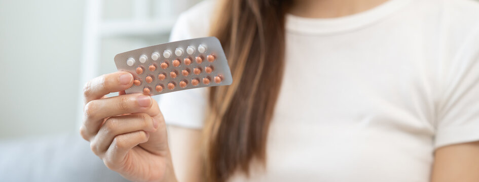 Contraception and pregnancy, menstruation concept, birth control pills asian young woman hand holding hormonal oral contraceptive medicine, take pharmaceutical to prevention, safe virus sex disease.