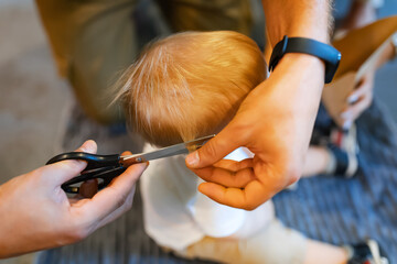 A man cuts a child's hair, top view. Customs for a one year old child. In motion, slight blurring