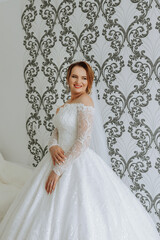 Fototapeta premium A woman in a white wedding dress is posing for a picture. She is smiling and she is happy