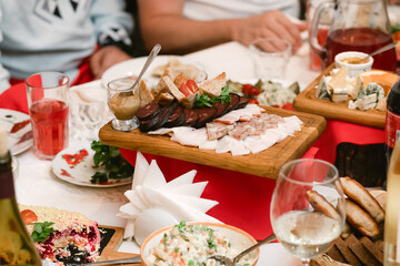 Ukrainian national cuisine. Sliced lard with mustard on a wooden board. A table with guests