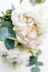The newlyweds' rings rest on an exquisite bouquet of flowers, wedding themed.