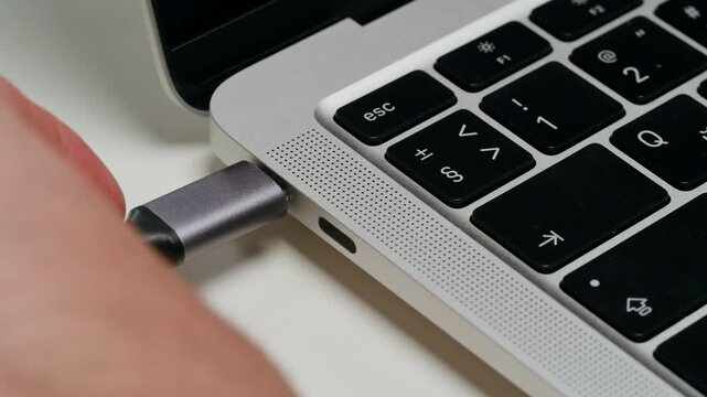 Charging connection to laptop on white table close-up . Phone charging port. USB wire for devices