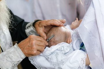 The priest cuts off the hair on the baby's head, church rites and traditions.
