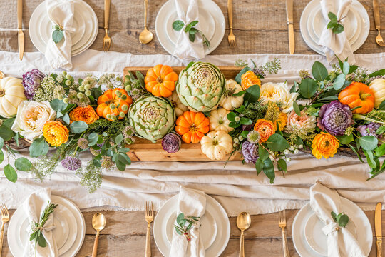 Overhead flat lay, fall autumn themed table setting with rustic pumpkin gourd artichoke garland centerpiece, dining
