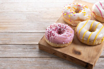 Sweet glazed donuts on wooden table. Copy space