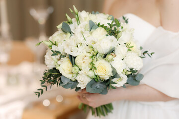 The bride is holding a wedding bouquet of flowers. Close-up