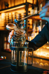 The waiter pours loose tea with a long spoon. 