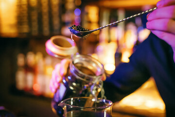 The waiter pours loose tea with a long spoon. 