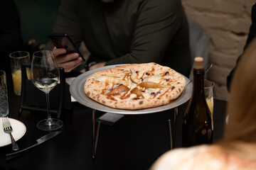 Big pizza on the table, people chatting in a non-formal setting.