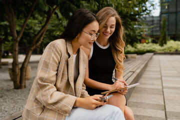 young pretty women sitting outside in street doing business