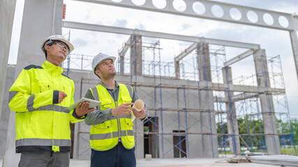 Two Asian engineer working at site of a large building project,Work overtime at construction site,Team of engineer discus at site,The architect, supervisor, and foreman meet to discuss the design