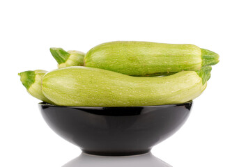 Several ripe zucchini in a black ceramic plate, macro, isolated on white background.