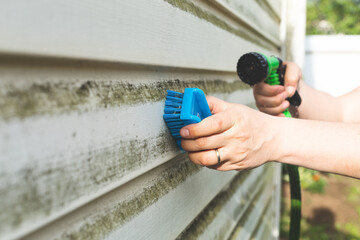 Cleaning algae and mold from vinyl siding of house with pressure spray jet. Home repair,...
