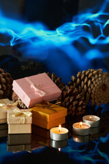 Gifts and candles arranged with pinecones against a blue background