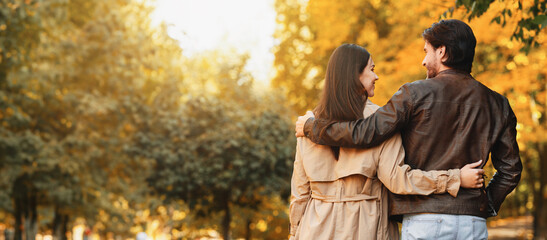 Couple hugging, talking and walking by autumn park, copy space