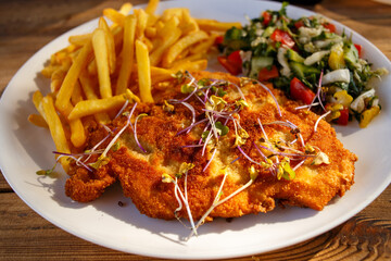 Appetizing food in a rustic style. French fries, meat and salad close-up on a white plate. Simple healthy nutrition. The ratio of proteins, fats and carbohydrates.