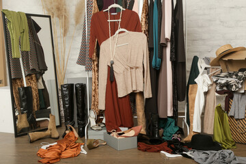 Untidy cluttered woman wardrobe with stylish clothes and accessories. Messy clothes thrown on a clothes rack, on the ground. Concept of over consumerism, shopaholic and compulsive buying disorder.