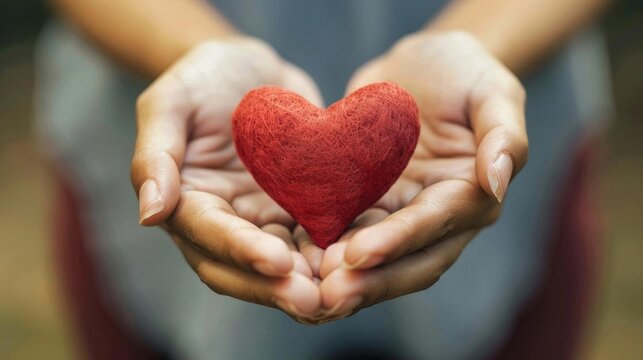 The woman is gently holding a red heart. Caring about relationship and feeling.