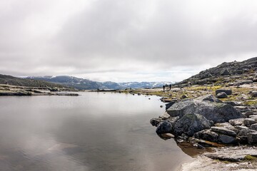 Clear water lake on trail to Trolltunga, Norway, unrecognizable hikers