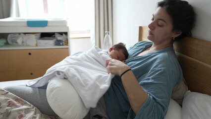 Fototapeta premium Mother holding sleeping newborn baby with a blanket, ensuring warmth and comfort, cozy indoor environment, intimate and peaceful moment, expression of love and care, family bonding