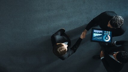 Top down aerial view of skilled businessman shake hands with smart executive manager. Slow motion of team working together to analyze stock investment data from tablet. Making agreement. Directorate.