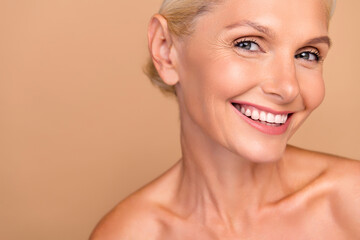 Photo of sweet positive woman naked shoulders smiling showing white teeth empty space isolated beige color background