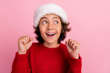 Photo of positive kid boy look empty space raise fists up on christmas isolated pastel color background