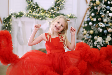 Happy girl in a red dress celebrating Christmas. A joyful young girl in a vibrant red dress smiles...