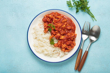 Delicious chicken curry with basmati rice on blue background. Top view shows homemade Indian meal. Spicy and tasty for lunch or dinner