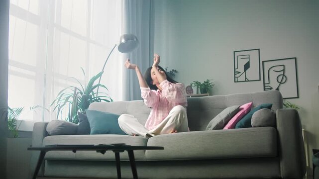 Cozy woman stretching and relaxing on living room sofa