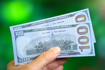 Mans hand holding 200 USD in fake or prop US 100 dollar bills