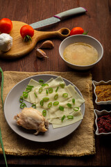 Dagestan khinkal homemade dough, meat, thick broth, garlic and herbs and sauce bowls with mustard and adjika on the table