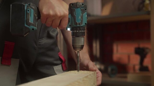 A person demonstrates woodworking techniques by using a power drill to create precise holes in a wooden plank