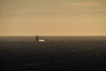 Obraz premium Freight ship steaming into the sunset.