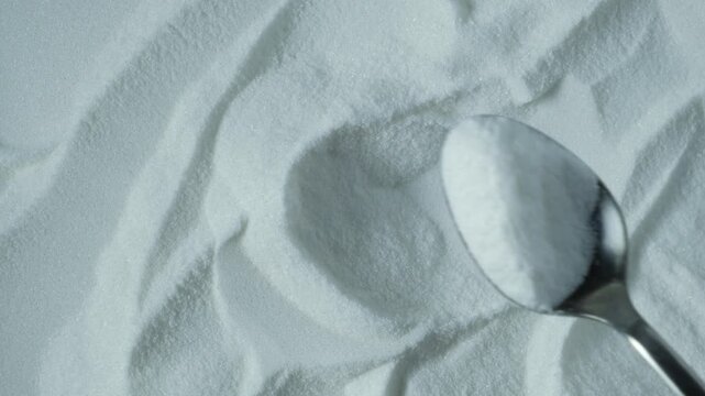 Food additive E316, close-up. Sodium erythorbate or isoascorbate powder in spoon.