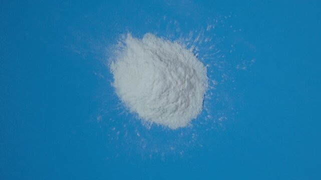 Pile of Transglutaminase TG, aka Meat Glue on blue surface. 4K Video, Rotating. Natural enzyme that has the ability to glue protein-containing foods together. White powder microbial TGase or MTGase.