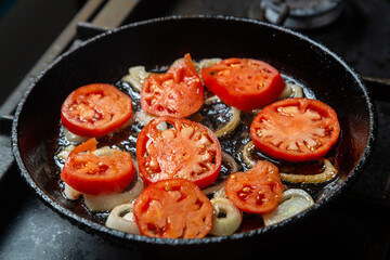 Tomatoes and onions are fried in a pan in boiling oil