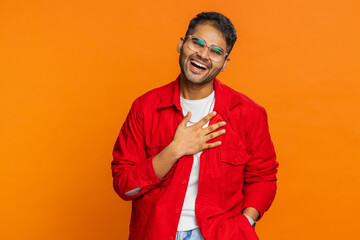 Happy Indian young man laughing out loud after hearing ridiculous anecdote, reaction on funny joke,...