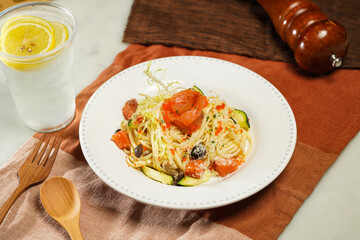 Linguine pasta with Crab Roe and Smoked Salmon in Japanese Style with lemonade, wooden spoon and fork served in plate isolated on napkin and dining table side view of italian food