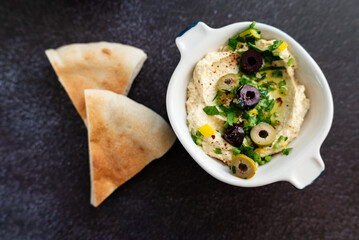 Traditional hummus with olives and olive oil. Gray grunge background.  Top view, flat lay, copy space