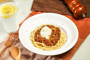 Wagyu Beef Bolognese with Soft Boiled Egg with lemonade, wooden spoon and fork served in plate isolated on napkin and dining table side view of italian food