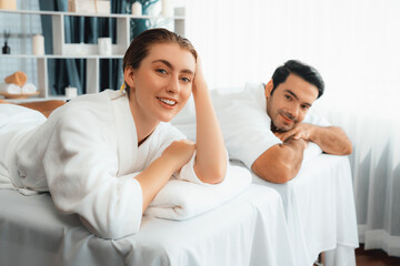 Fototapeta premium Caucasian couple customer enjoying relaxing anti-stress spa massage and pampering with beauty skin recreation leisure in day light ambient salon spa at luxury resort or hotel. Quiescent