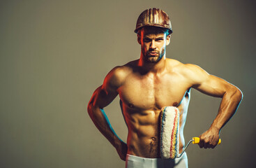 Painter man with paint roller. Repair, redecoration and renovation. Sexy handsome man in hard hat...