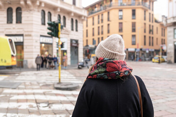 Woman with cap and scarf walking in Milan