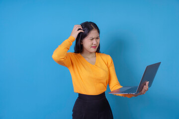 Young professional woman is scratching her head while holding a laptop, looking confused and unsure
