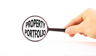 Property portfolio symbol. Concept words Property portfolio in beautiful magnifying glass. Beautiful white paper background. Businessman hand. Business Property portfolio concept. Copy space.