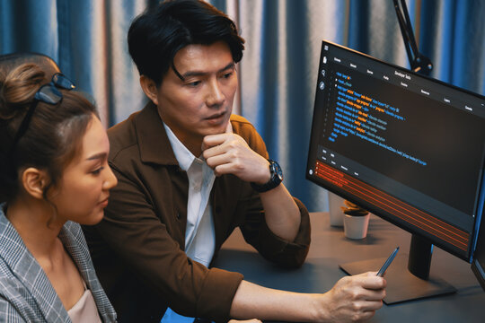 IT developers discussing with point to intelligent website development coder system running data online two screens information technology at neon light room at modern office. Infobahn.