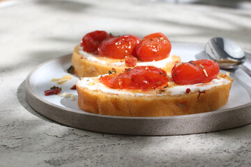 Traditional Italian bruschetta with cherry tomatoes, cream cheese and seasonings on a round plate.